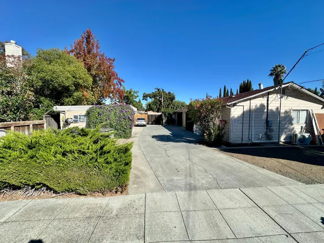 a view of house with sign board and a yard