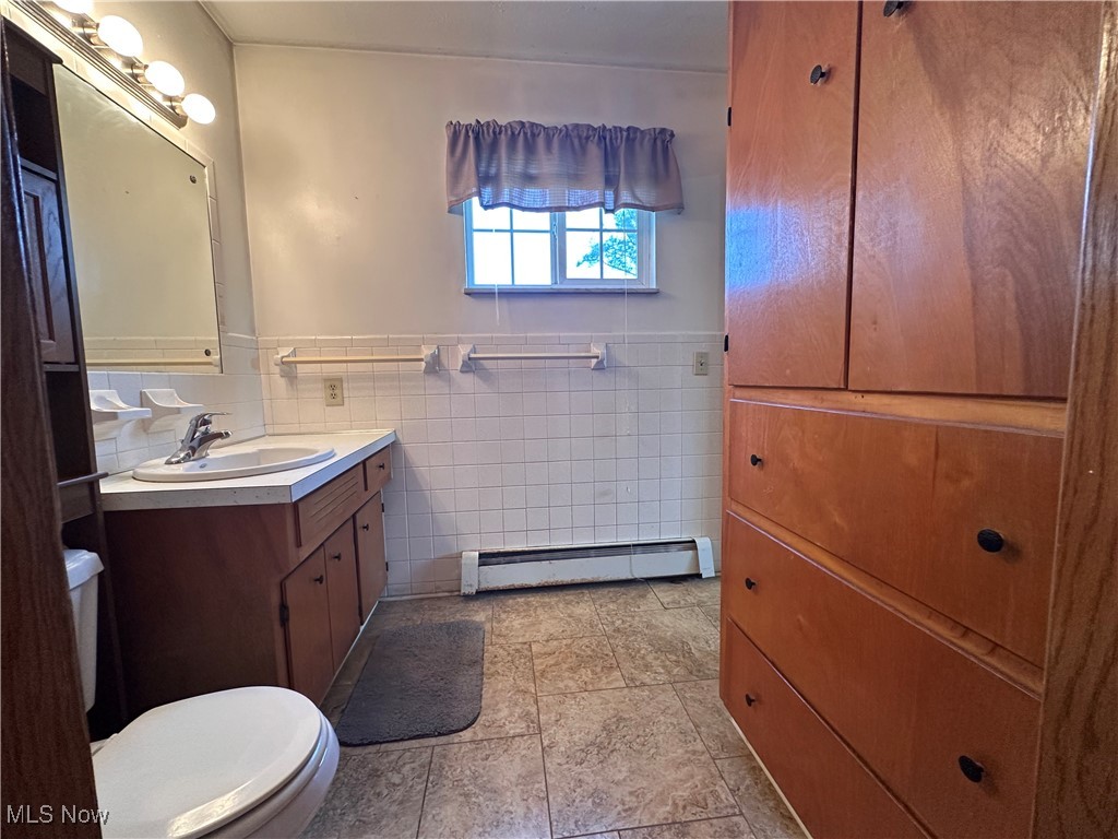 2829 Shellhart Road Barberton, OH 44203 - Photo 11 of 29 Bathroom featuring tile walls, vanity, toilet, and baseboard heating