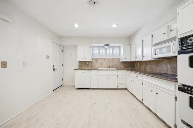 a kitchen with granite countertop white cabinets white stainless steel appliances with a sink and dishwasher