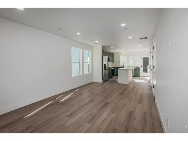 a view of an empty room with wooden floor and window