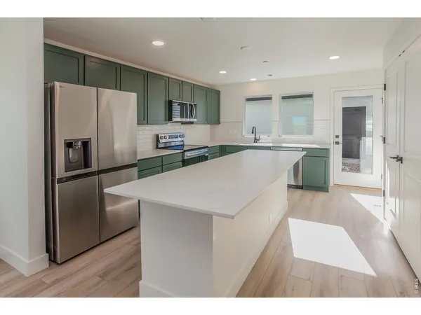 a kitchen with stainless steel appliances granite countertop a refrigerator a stove top oven and sink