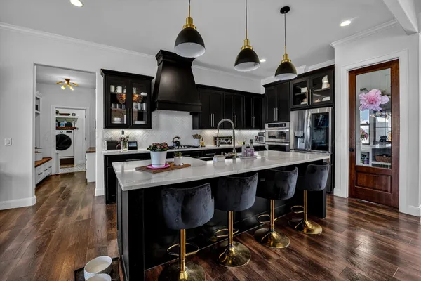 a kitchen with stainless steel appliances granite countertop a stove a refrigerator a sink a dining table and chairs with wooden floor