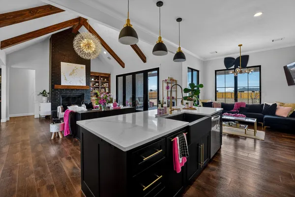 a kitchen with a stove a counter top space a sink and living room view