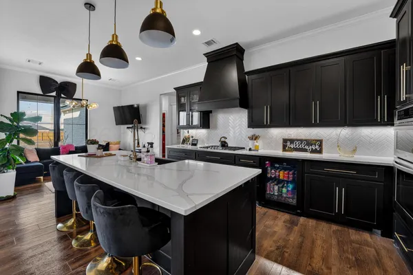 a kitchen with a stove a kitchen island with chairs and wooden cabinets