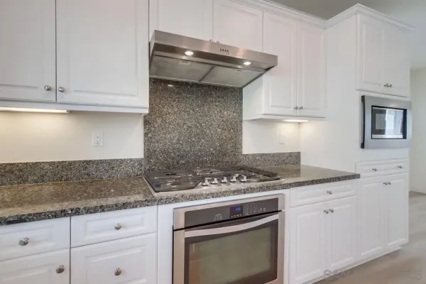 a kitchen with granite countertop white cabinets and white appliances