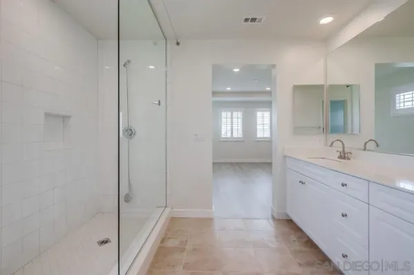 a spacious bathroom with a granite countertop sink a mirror and a shower