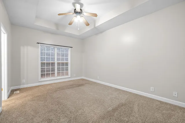 an empty room with windows and fan