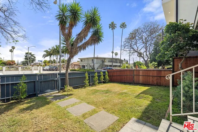 a view of a backyard with potted plants and large trees