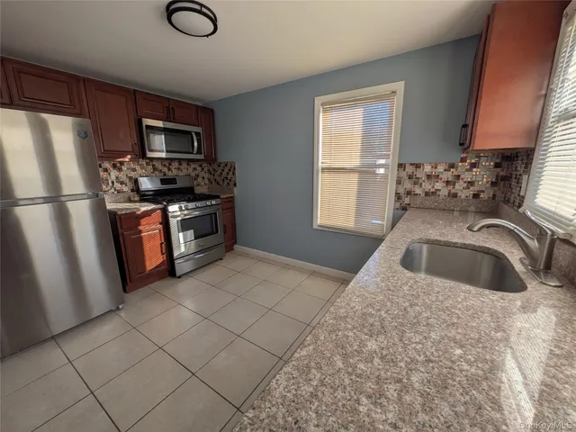 a kitchen with stainless steel appliances granite countertop a sink stove refrigerator and a window