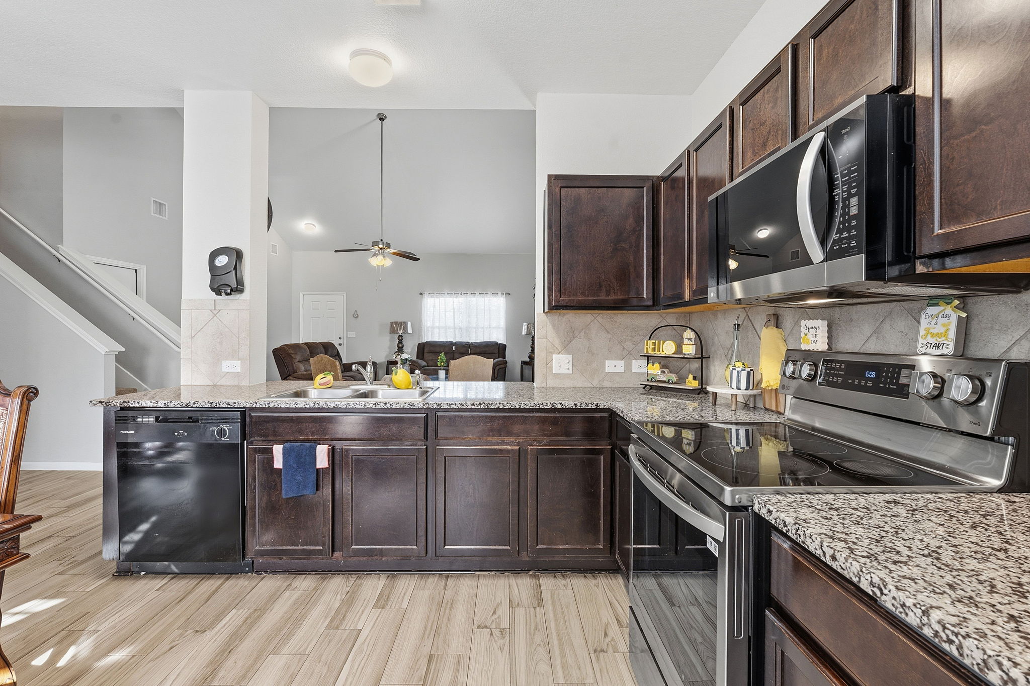 15101 Shell Bark Cove Austin, TX 78724 - Photo 11 of 26 Kitchen featuring wood-finish flooring, dark wood cabinetry, and speckled granite countertops