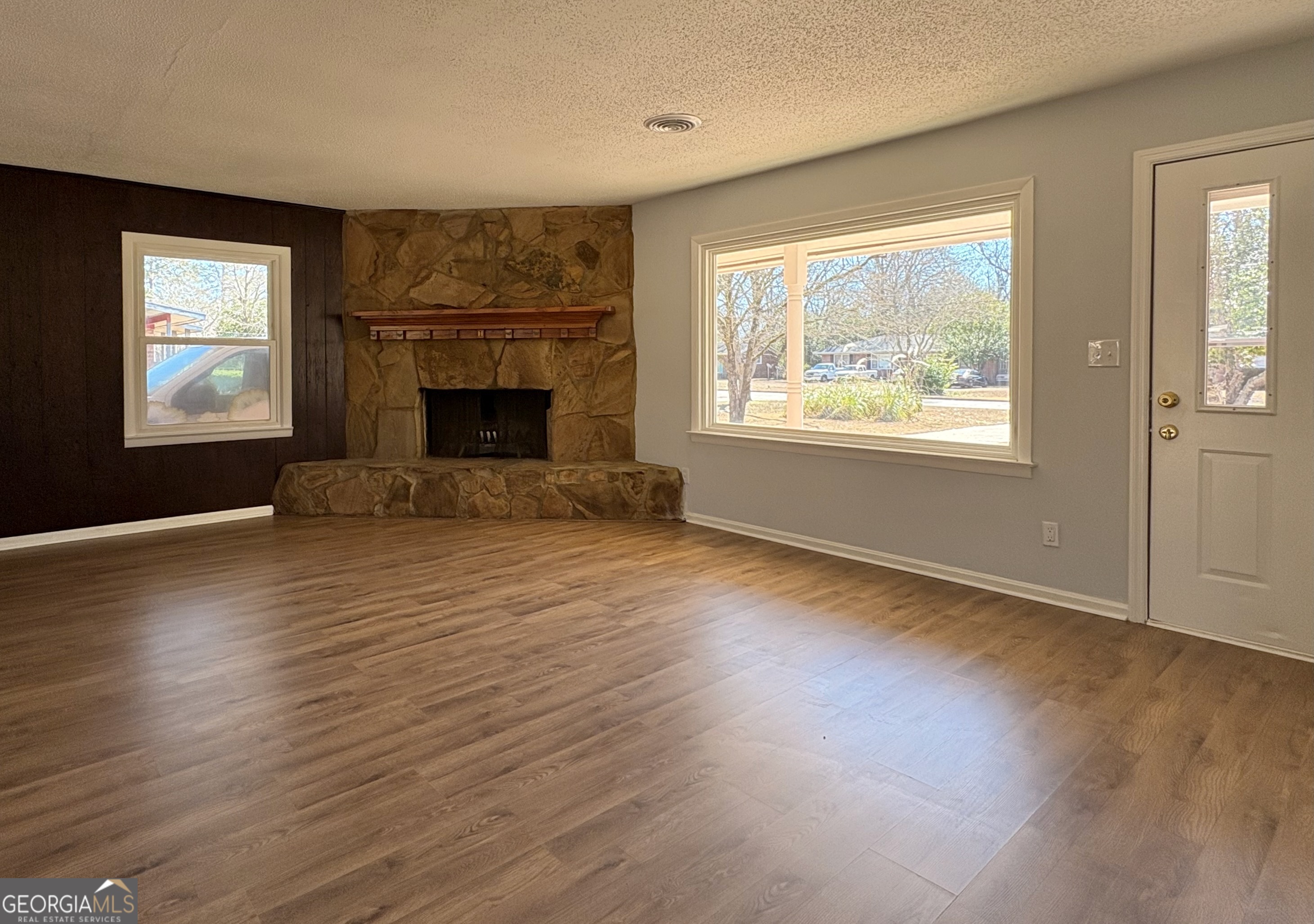 404 Magnolia Street Fort Valley, GA 31030 - Photo 4 of 21 an empty room with windows a fireplace and wooden floor