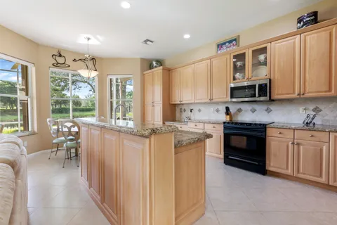 a kitchen with granite countertop a stove top oven a sink a dining table and chairs