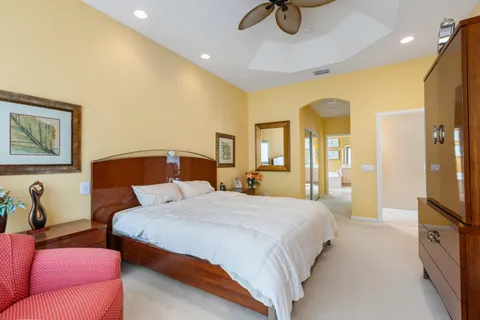 a bedroom with a bed a couch and a flat tv screen on the dresser