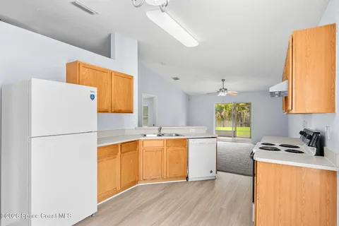a kitchen with a refrigerator a stove a sink dishwasher and white countertops with wooden floor