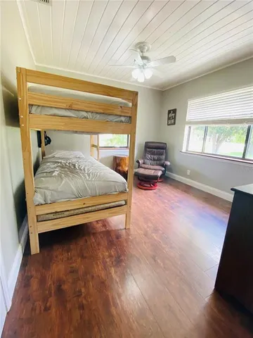 a bedroom with a bed and a large window with wooden floor