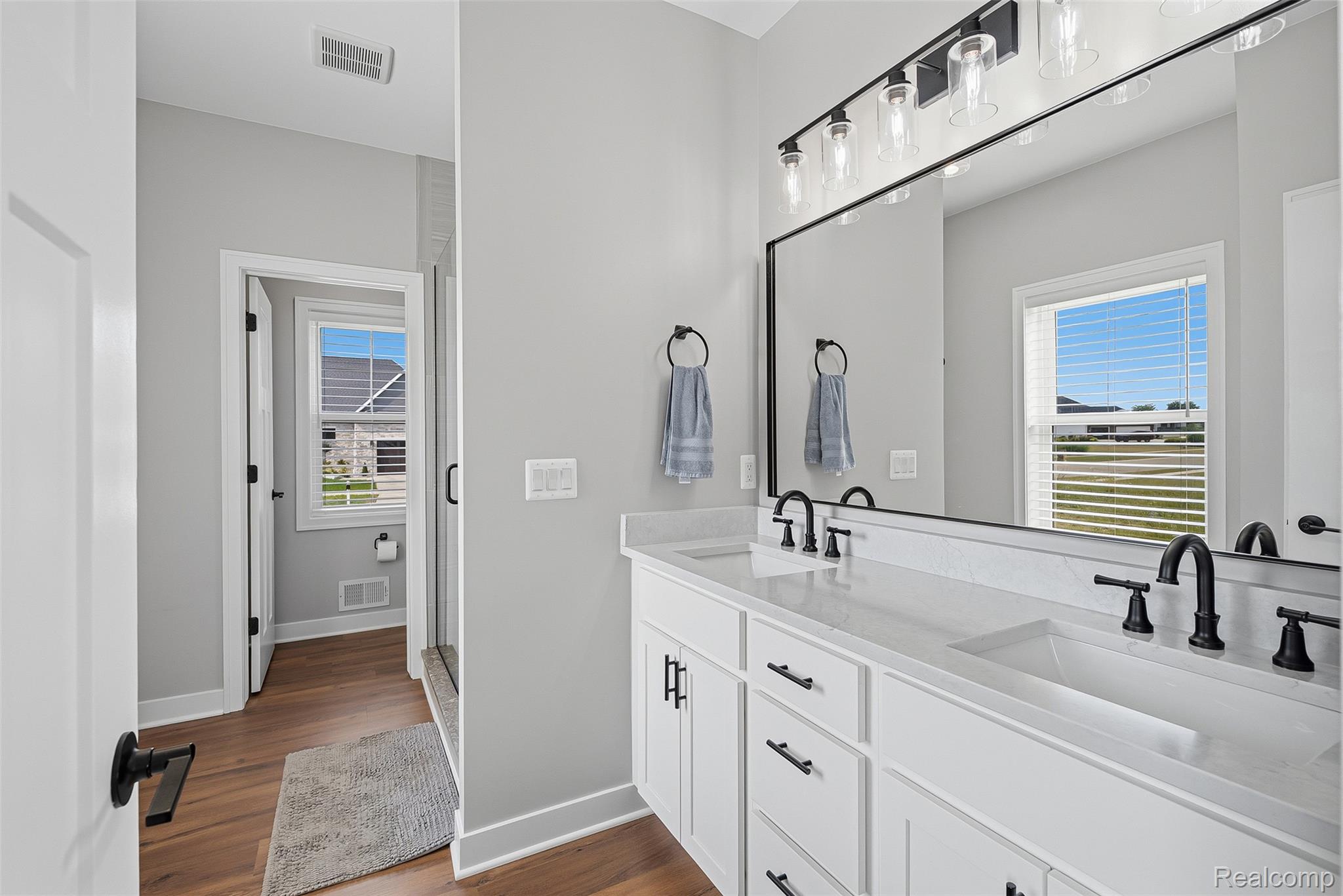 9087 Copper Ridge Drive Davison, MI 48423 - Photo 30 of 46 Dual vanity with white cabinetry, integrated sinks, black fixtures, and a coordinating framed mirror
