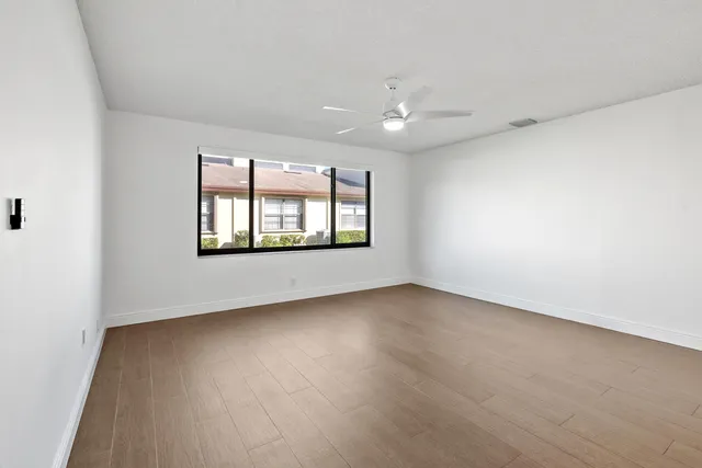 an empty room with wooden floor and windows