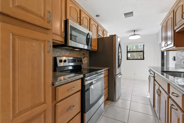 a kitchen with stainless steel appliances granite countertop a refrigerator a stove a sink and a microwave
