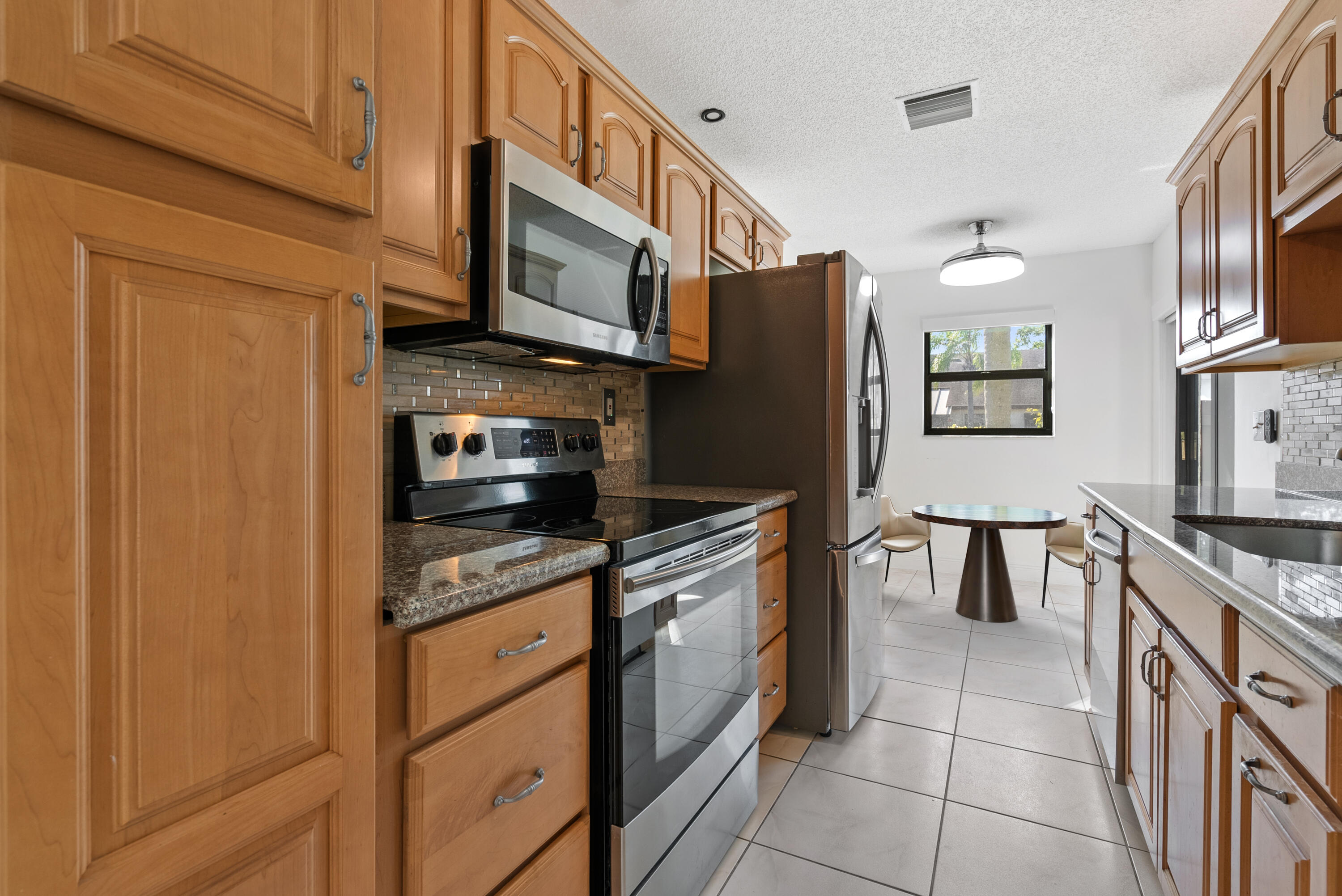 5110 Nesting Way, Unit B Delray Beach, FL 33484 - Photo 3 of 29 a kitchen with stainless steel appliances granite countertop a refrigerator and a stove top oven