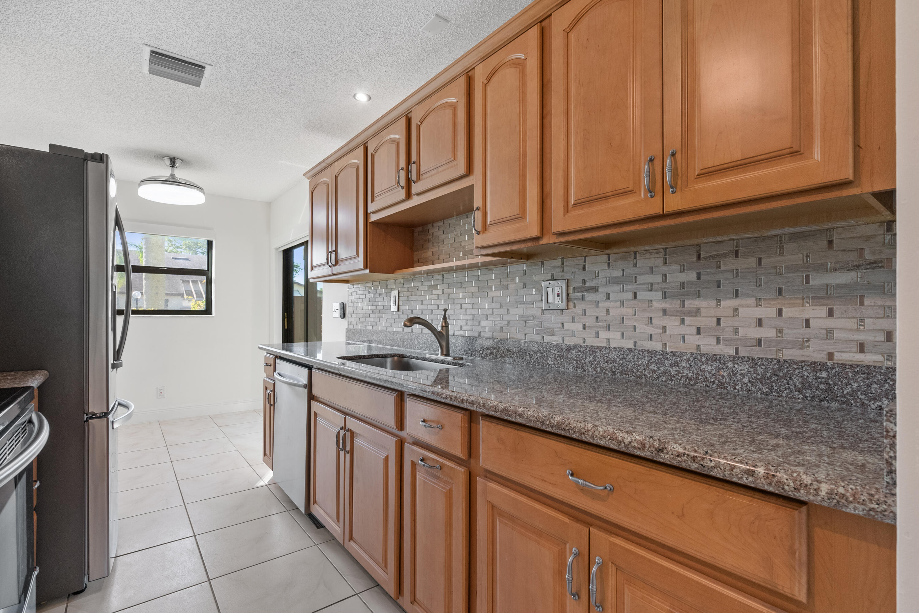 5110 Nesting Way, Unit B Delray Beach, FL 33484 - Photo 4 of 29 a kitchen with stainless steel appliances granite countertop a sink stove and refrigerator