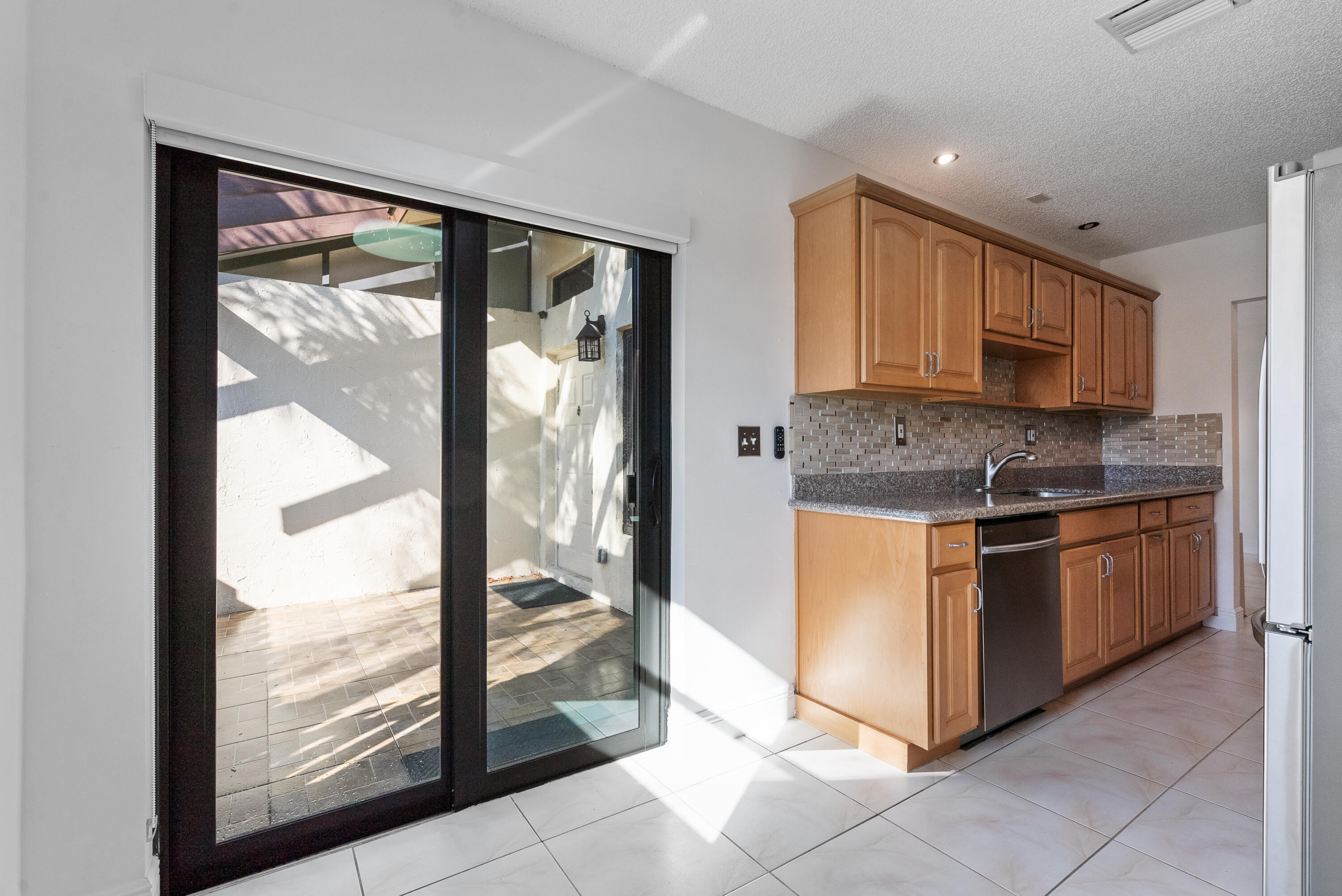 5110 Nesting Way, Unit B Delray Beach, FL 33484 - Photo 5 of 29 a kitchen with stainless steel appliances granite countertop a stove top oven a sink and a granite counter top
