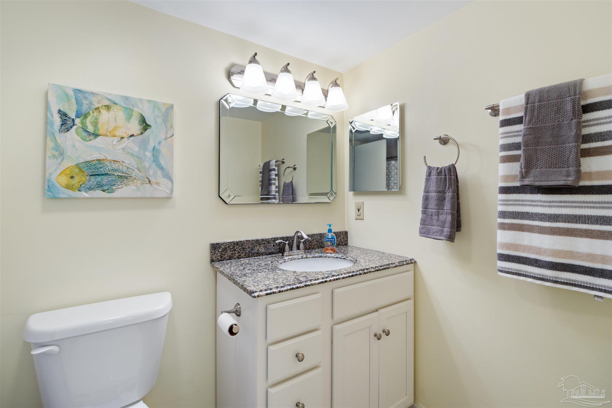 14100 River Road, Unit 228B Pensacola, FL 32507 - Photo 21 of 41 a bathroom with a granite countertop sink a toilet and a mirror