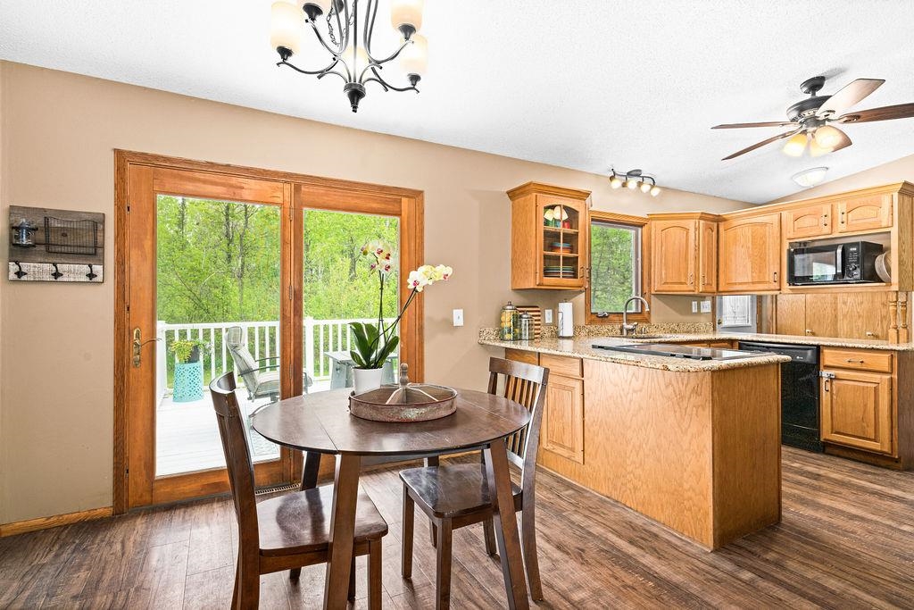 20 Canosia Road Esko, MN 55733 - Photo 6 of 29 Kitchen featuring black refrigerator with ice dispenser, dark wood-type flooring, light stone counters, and arched walkways