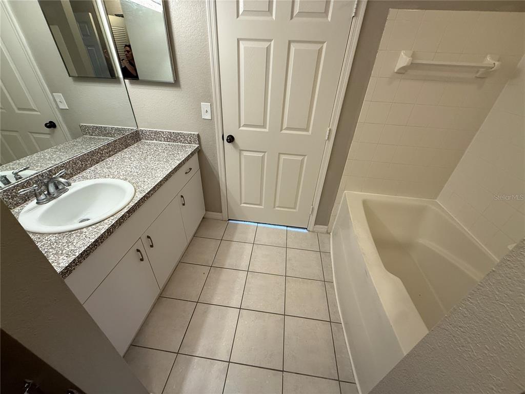 6312 Raleigh Street, Unit 512 Orlando, FL 32835 - Photo 6 of 17 a bathroom with a granite countertop sink and a mirror
