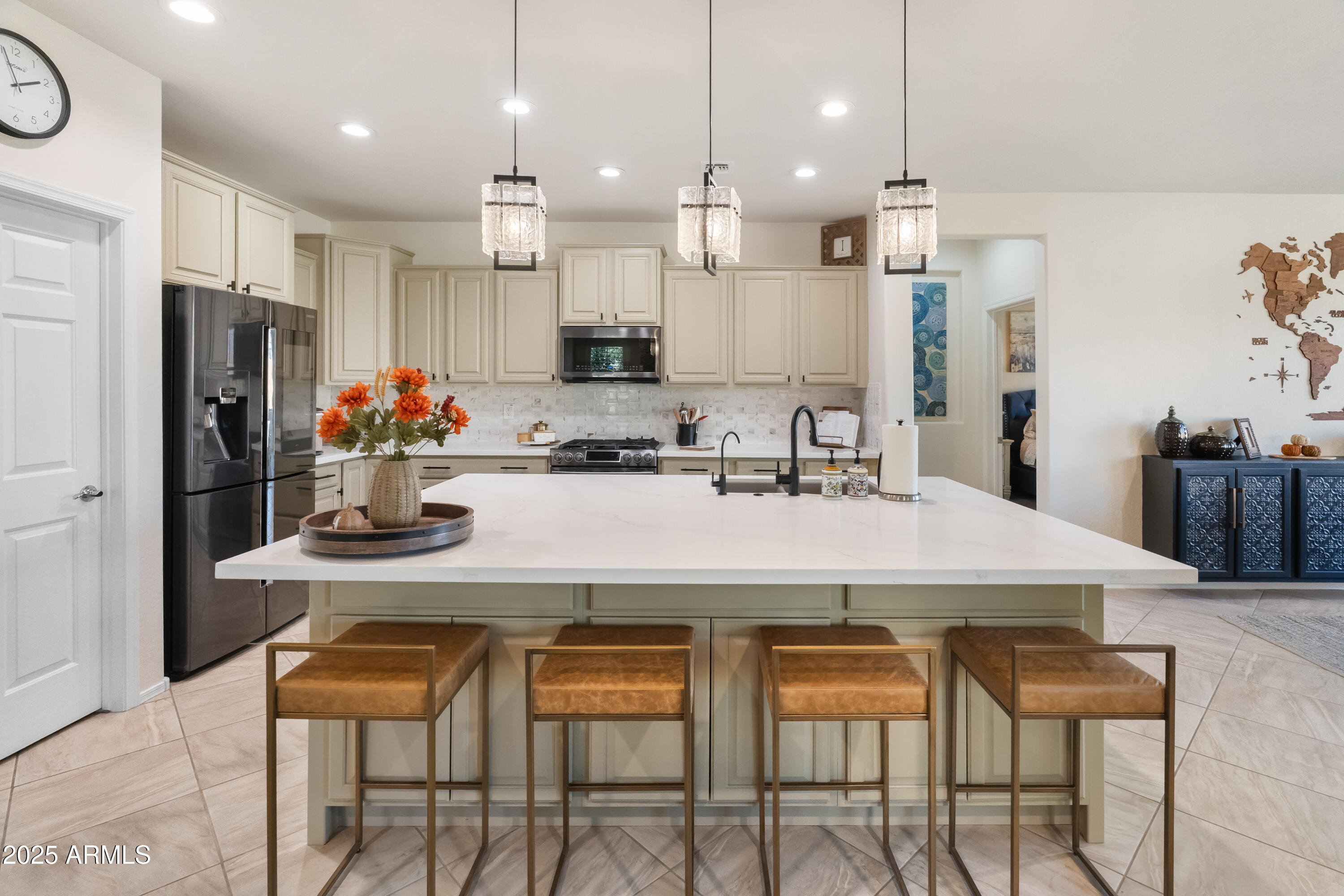 26990 West Utopia Road Buckeye, AZ 85396 - Photo 8 of 41 a kitchen with stainless steel appliances kitchen island granite countertop a dining table chairs refrigerator and microwave