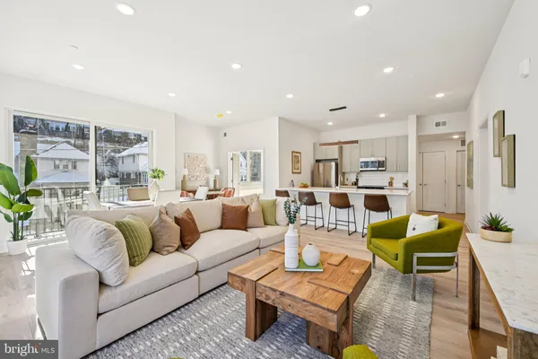 a living room with furniture kitchen view and a large window