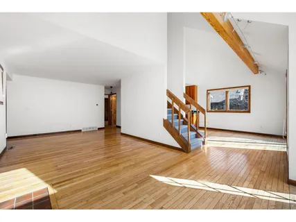 a view of an empty room with wooden floor and stairs