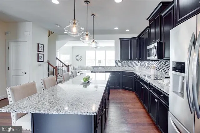 a kitchen with kitchen island granite countertop a sink a counter top space and stainless steel appliances