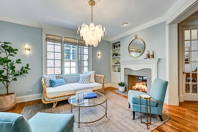 a living room with furniture a chandelier a large window and wooden floor