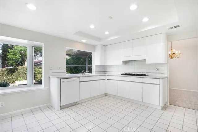 a kitchen with white cabinets a sink and a stove top oven