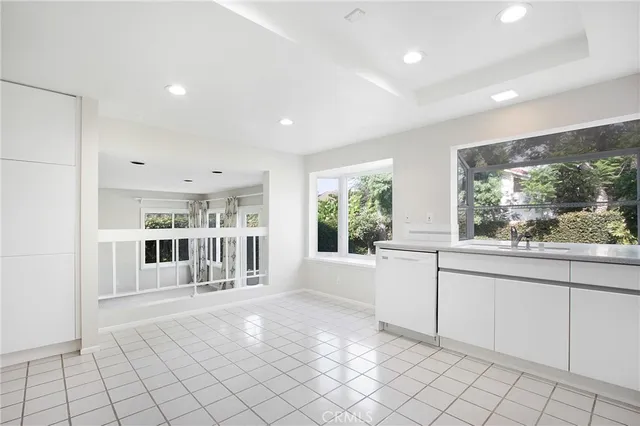 a view of open kitchen with white cabinets and outdoor space