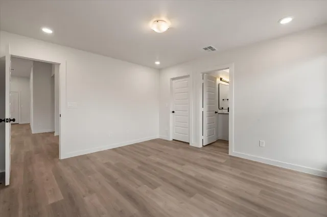 an empty room with wooden floor & windows closet