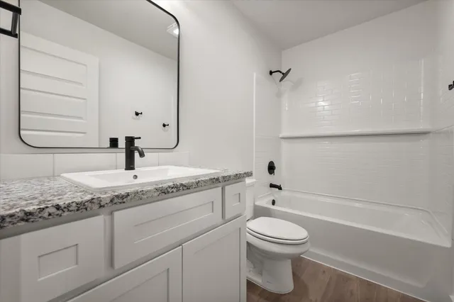 a bathroom with a granite countertop sink a toilet and a bathtub