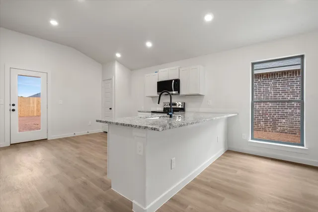 a large white kitchen with wooden floor and a refrigerator