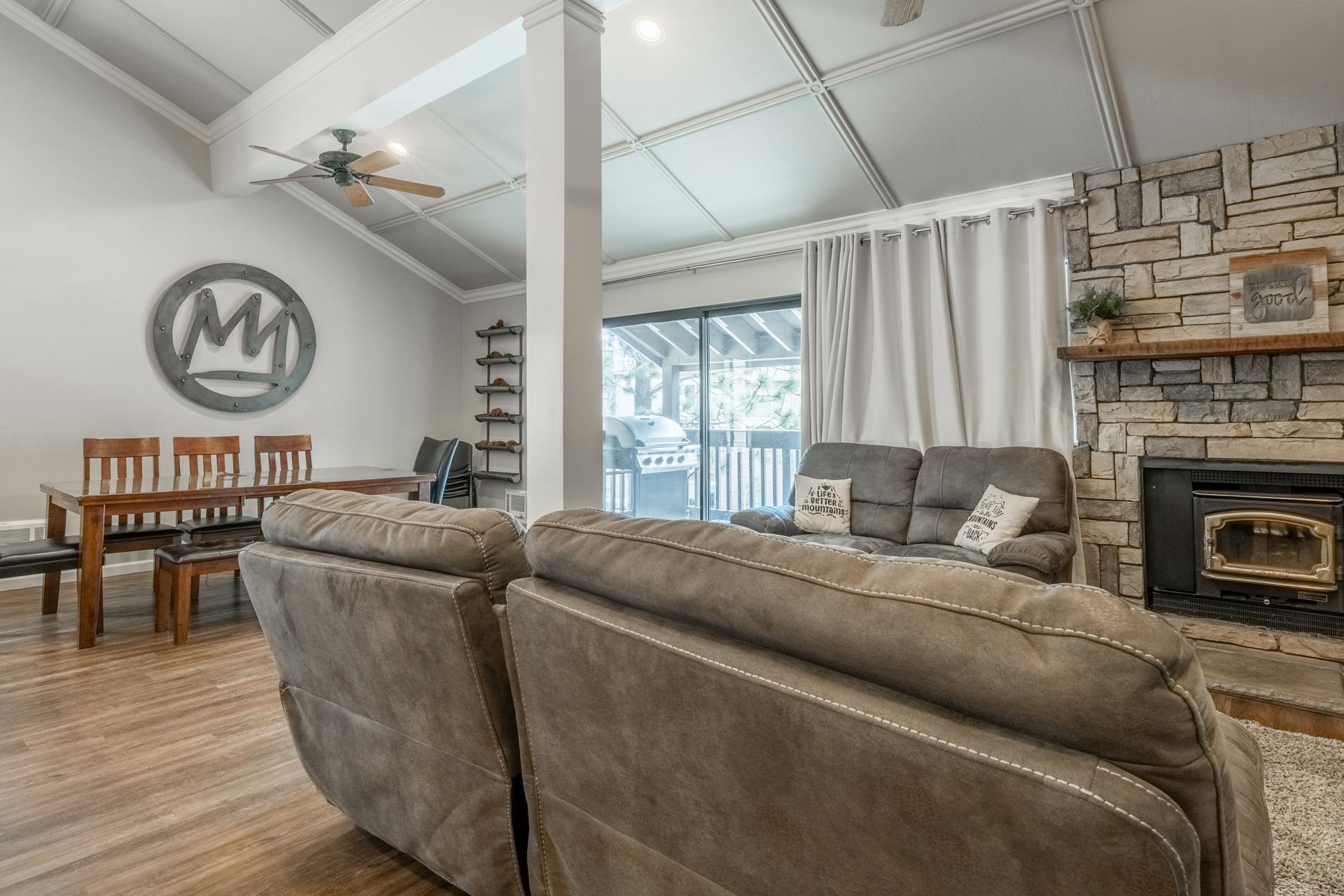 362 Old Mammoth Road, Unit 4 Mammoth Lakes, CA 93546 - Photo 3 of 50 Living area with wood finished floors, a ceiling fan, lofted ceiling, coffered ceiling, and a wood stove