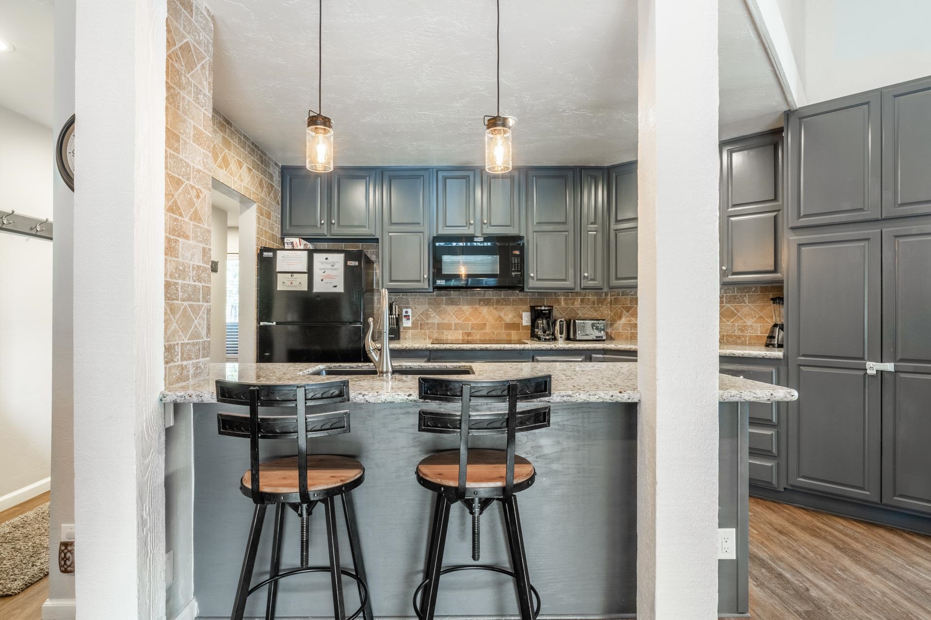 362 Old Mammoth Road, Unit 4 Mammoth Lakes, CA 93546 - Photo 9 of 50 Kitchen featuring gray cabinets, a breakfast bar area, black appliances, and light stone counters