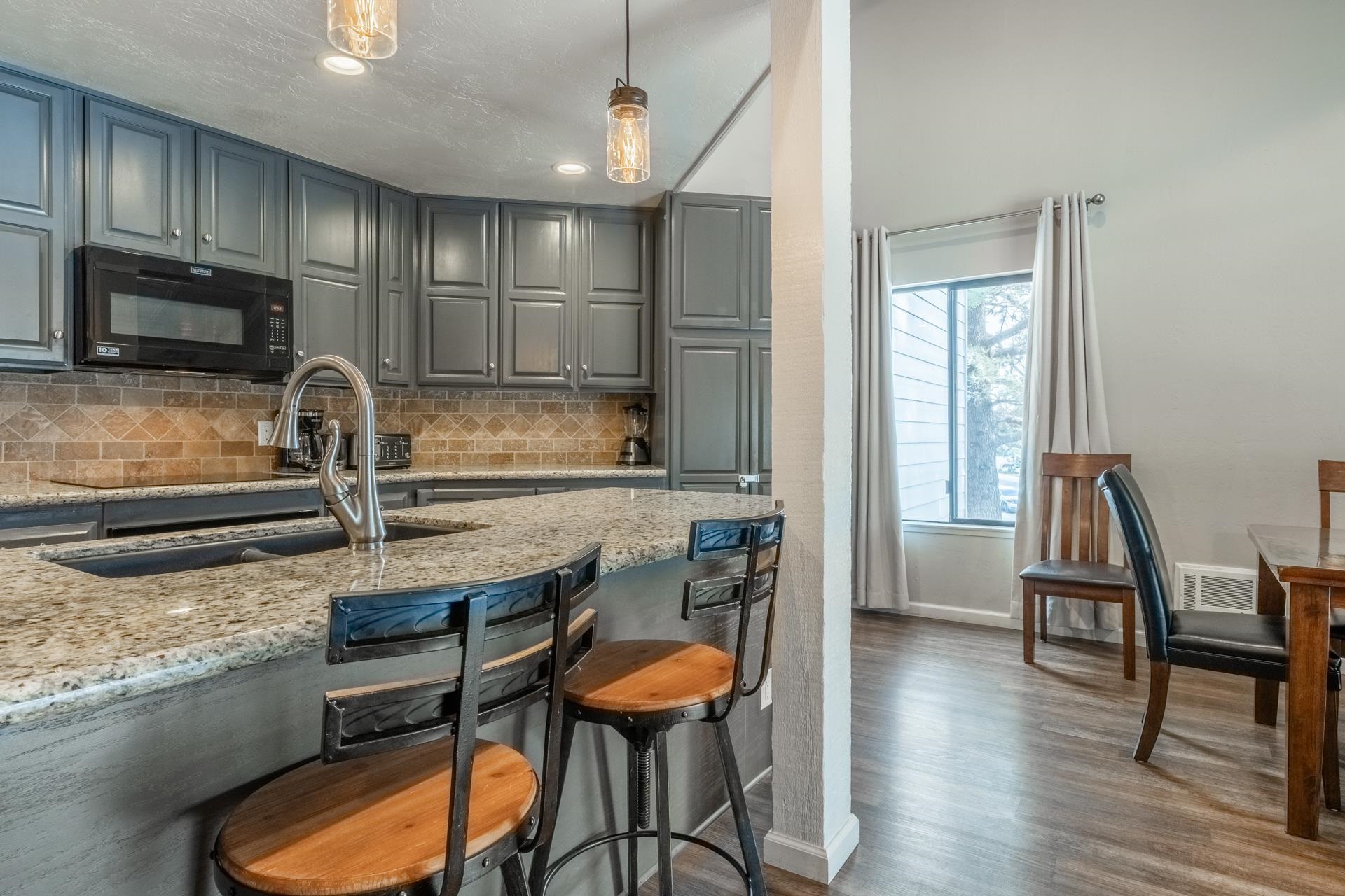 362 Old Mammoth Road, Unit 4 Mammoth Lakes, CA 93546 - Photo 10 of 50 Kitchen with gray cabinetry, pendant lighting, black microwave, dark wood-style floors, and backsplash