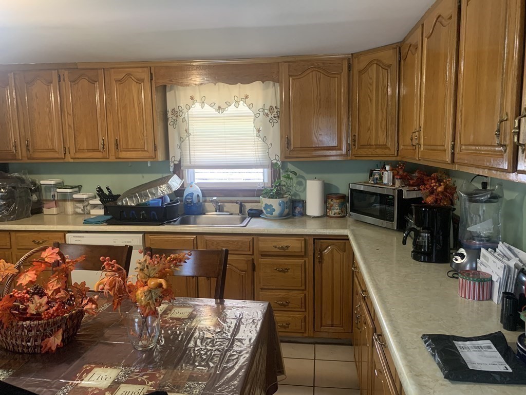 34 Grove Street Lynn, MA 01905 - Photo 20 of 37 a kitchen with granite countertop a stove a sink and dishwasher wooden cabinets with a dining table