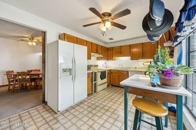 a kitchen with stainless steel appliances kitchen island granite countertop a table chairs and a refrigerator