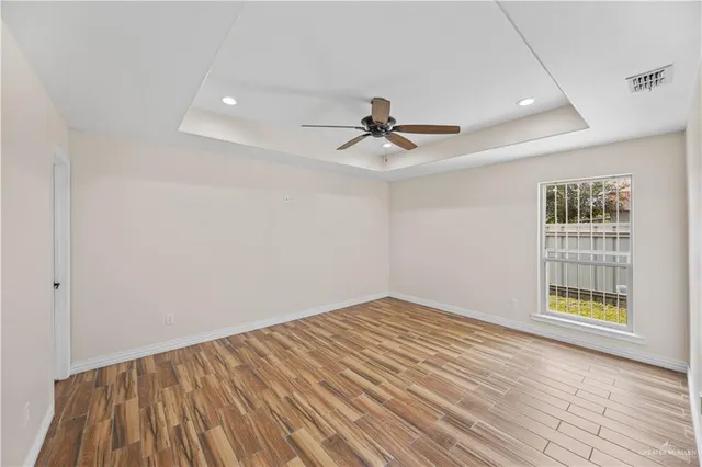 a view of empty room with wooden floor and fan