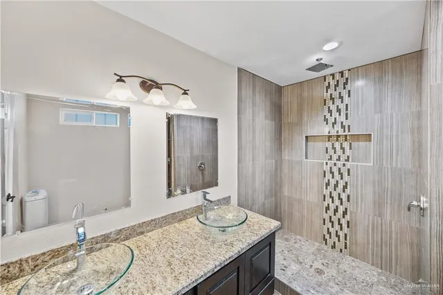 a bathroom with a granite countertop sink a toilet and shower