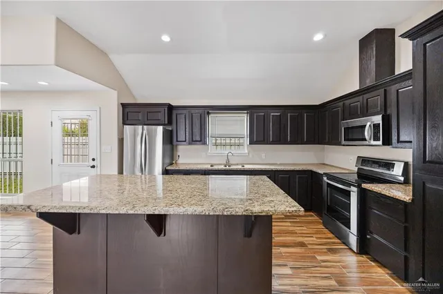 a kitchen with stainless steel appliances granite countertop a sink dishwasher stove and refrigerator