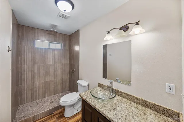 a bathroom with a granite countertop sink a toilet and a mirror