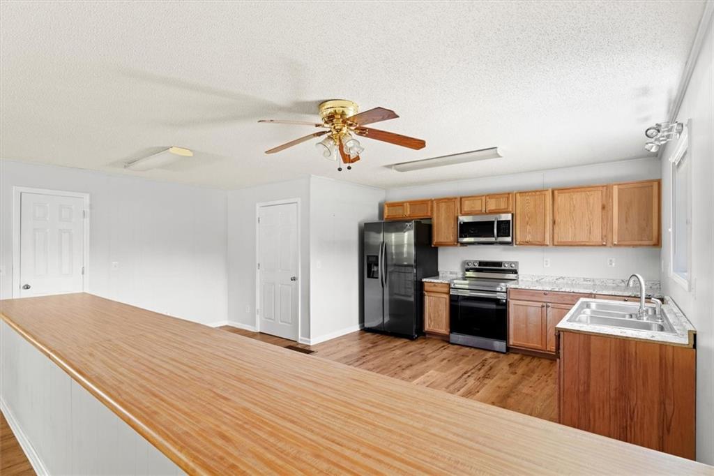 210 Hood Street Calhoun, GA 30701 - Photo 28 of 59 a kitchen with stainless steel appliances granite countertop a refrigerator a stove top oven a sink dishwasher and white cabinets with wooden floor