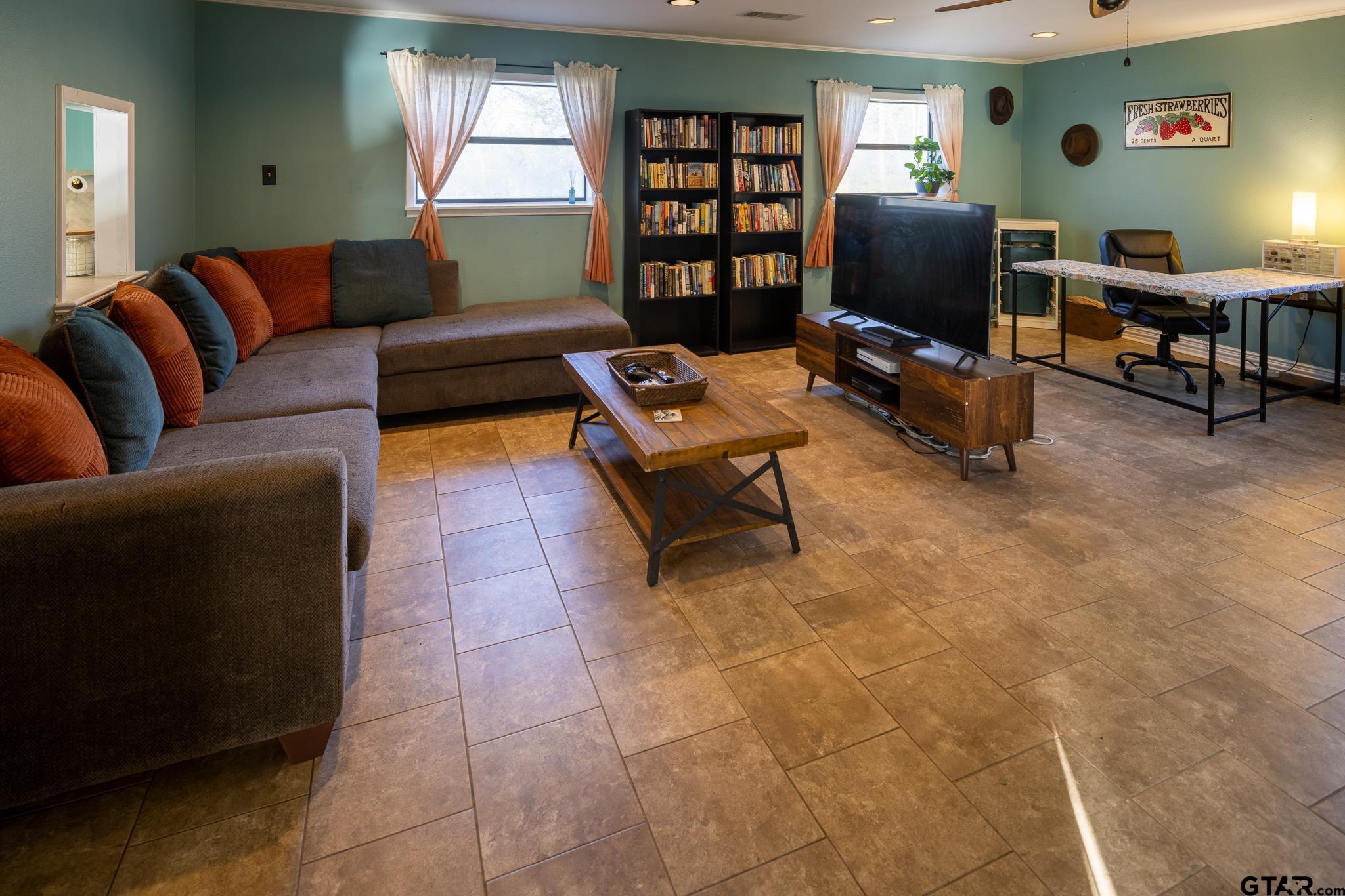 10733 County Road 4150 Tyler, TX 75704 - Photo 20 of 48 a living room with furniture a bookshelf and a flat screen tv