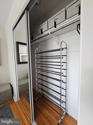 a view of a hallway with wooden floor and a bathroom